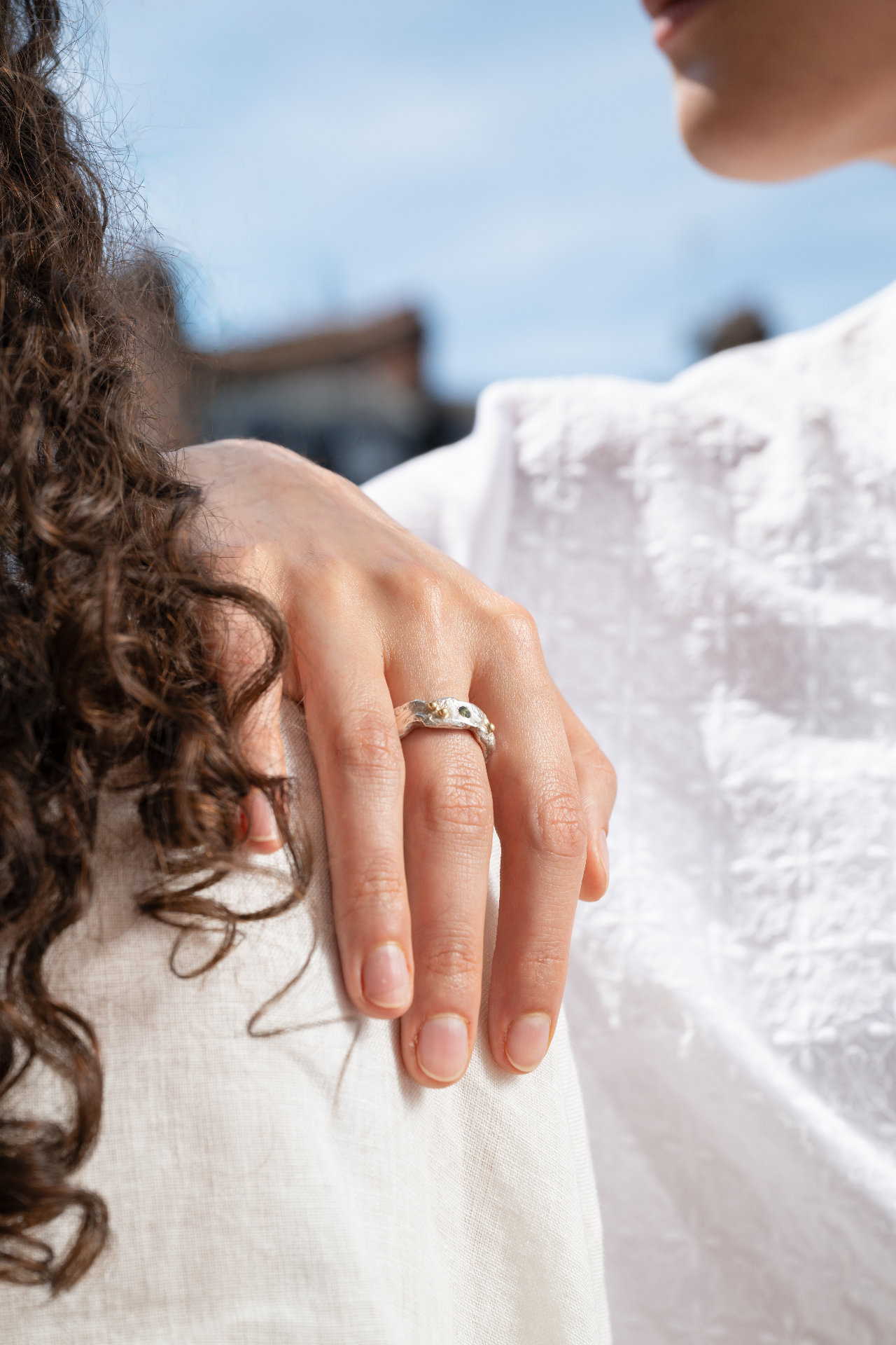 Handmade Joon silver ring with gold detail resting on a bare shoulder